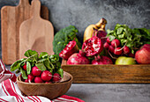 Bunch of fresh raw radish in wooden bowl, fresh fruit, greens, vegetables in wooden tray