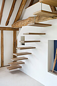 Floating staircase in room with wooden beams in converted barn
