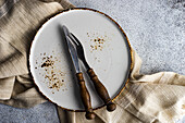 Rustic place setting with natural textile and plate on concrete background