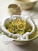 elderflowers with lemon slices being drained through a colander