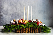 Weihnachtsdekoration mit Tannenzapfen, Zweigen, Früchten und Kerzen