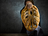 A hand holding a fougasse