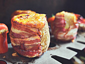Stuffed baked potatoes wrapped with bacon and topped with cheese