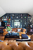 Cognacfarbene Ledersofas, Couchtisch und raumhohes Bücherregal im Wohnzimmer
