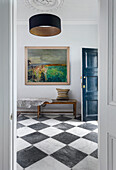 Elegant hall with checkered marble floor, wooden bench, and framed art