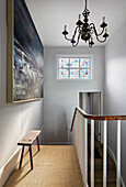 Staircase landing with stained glass window, dramatic artwork under rustic oak bench