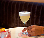 Hand holding a Pisco Sour cocktail