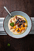 Millet porridge with persimmon, blueberries, banana, pecans and linseed oil