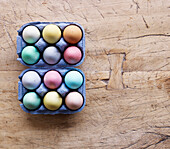 Coloured Easter eggs in egg boxes on a wooden surface
