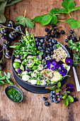 Berry avocado bowl with quinoa, green tomotoes and green herbs oil