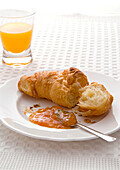 Croissant with apricot jam and glass of fruit juice
