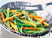 Steamed asparagus and thin slices of carrot in a colander