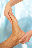 Reflexologist massaging man's foot
