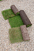 Three types of new rolled up turf on gravel