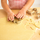 Pair of hands pressing cookie cutter on dough