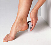 Woman using pumice on heel of foot