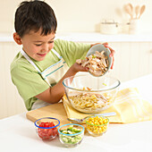 Boy making chicken and sweetcorn pasta salad
