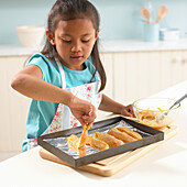Girl laying out marinated chicken strips on a baking tray