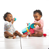 Twin girl and boy sitting playing with toy picnic basket