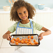 Girl holding a baking tray of salmon pieces on skewers