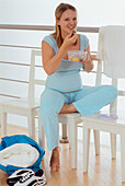 Pregnant woman sitting on chair eating fruit from bowl