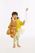 Little girl in fairy costume playing with bear
