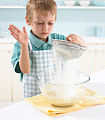 Boy sifting flower over banana butterfly cake mixture