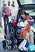 Woman sitting on back of car breastfeeding