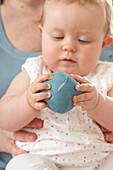 Baby girl holding a blue fabric ball