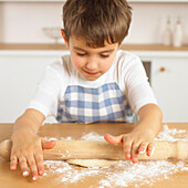 Boy rolling dough on a counter with a rolling pin