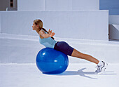 Woman lying on fitness ball doing stretching exercise