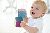 Baby boy sitting with knitted building blocks