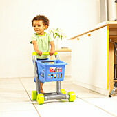 Boy pushing toy supermarket trolley