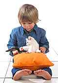 Boy sitting with kitten on cushion on lap