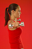 Woman lifting two dumbbells sideways to shoulder height
