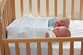 Twin girls asleep together in cot