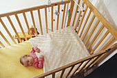 Baby girl sleeping in wooden crib