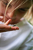 Girl holding tiny frog on finger