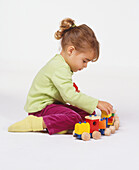 Girl kneeling on floor playing with toy train