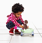 Toddler girl sitting doll on portable potty