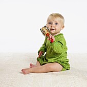 Baby girl holding wooden rattle