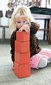 Girl stacking red cubes in size order