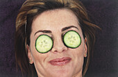 Woman lying with two cucumber slices on each eye
