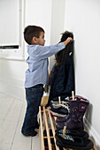 Boy hanging coat on wall