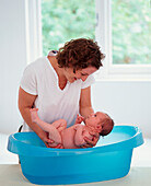 Woman lifting baby out of baby bath