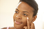 Woman applying oil to under eye area