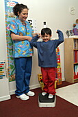 Boy standing on scales next to nurse
