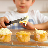 Boy holding knife with icing over cupcake