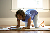 Pregnant woman on all fours reading a magazine