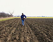 Man sowing seeds by hand in ploughed field